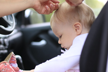 Sad baby in the car and the woman's hands are making the hair styleの写真素材