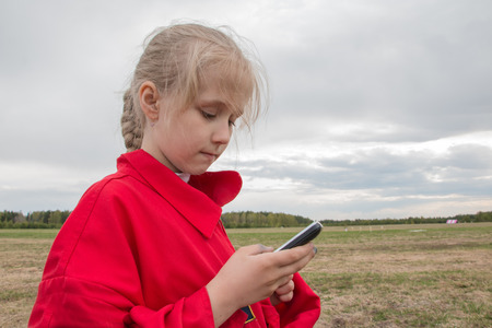 Girl with cell phone and cloudy sky backgroundの写真素材