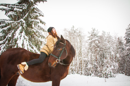Young girl and horse in a white winter forestの写真素材