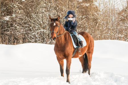 Small girl and horse in a winter dayの写真素材