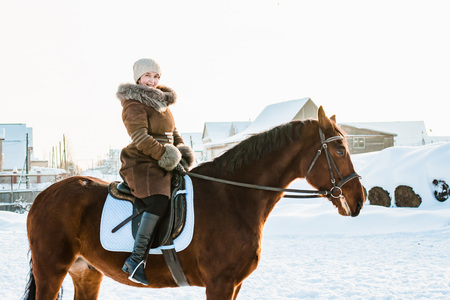 Woman in brown dress and brown horse in a winter dayの写真素材