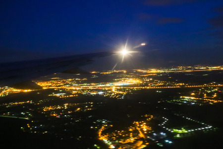 The wing of an airplane flying in the sky and nighe lightsの写真素材
