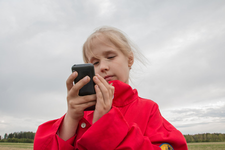 Girl with cell phone and cloudy sky backgroundの写真素材
