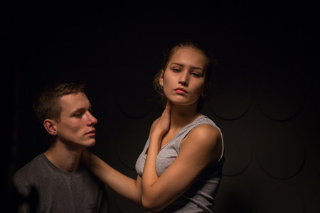 Passionate young couple in the room and the darkness aroundの写真素材