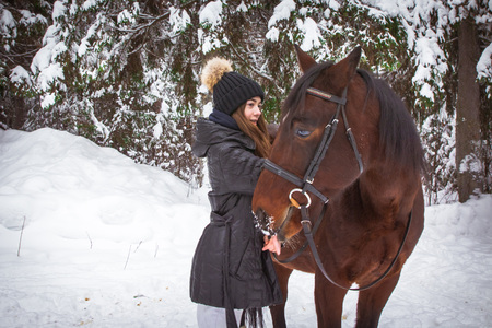 Young girl and horse in a white winter forestの写真素材