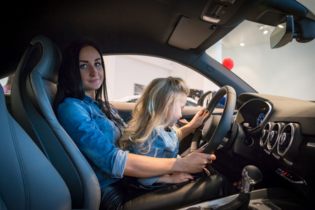Small girl and mom in exhibition hall for carの写真素材