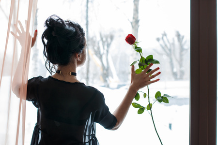 Girl with black hair in black clothes near the windowの写真素材