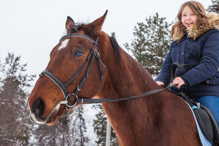 Girl teenager and big horse in a winter dayの写真素材