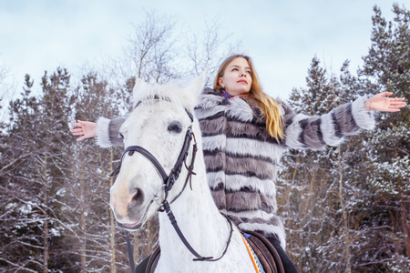 Nice girl and white horse in a forest in a winter dayの写真素材