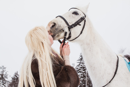 Nice girl and white horse outdoor in a winter dayの写真素材