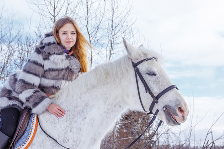 Nice girl and white horse in a forest in a winter dayの写真素材
