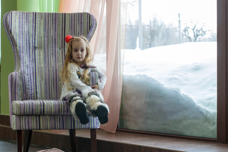Beautiful little girl with white hair near the windowの写真素材