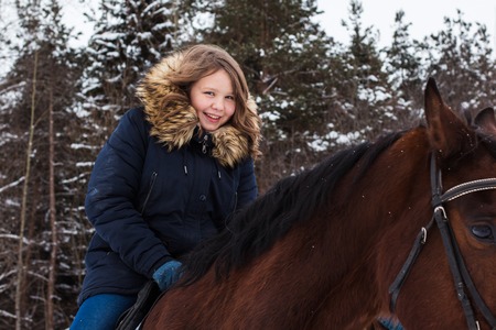 Girl teenager and big horse in a winter dayの写真素材