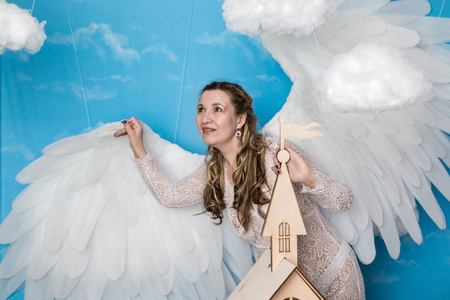 Ugly woman in a white dress with white wings is trying to look as angelの写真素材