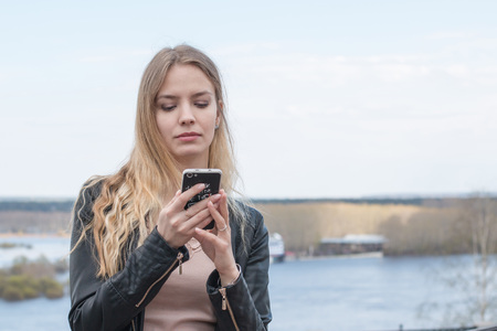Girl with cell phone and river backgroundの写真素材