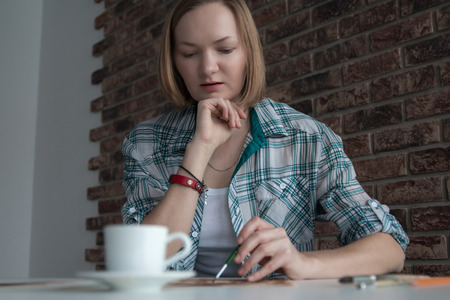 Female artist with blond hair draws in the roomの写真素材