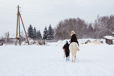 Girl, horse trainer and white horse on a winter dayの写真素材