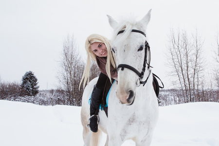 Nice girl and white horse outdoor in a winter dayの写真素材