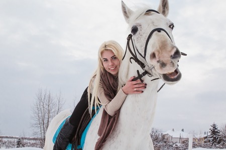 Nice girl and white horse outdoor in a winter dayの写真素材
