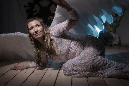 Ugly woman in a white dress with white wings is trying to look as angelの写真素材