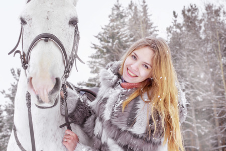 Nice girl and white horse outdoor in a winter dayの写真素材