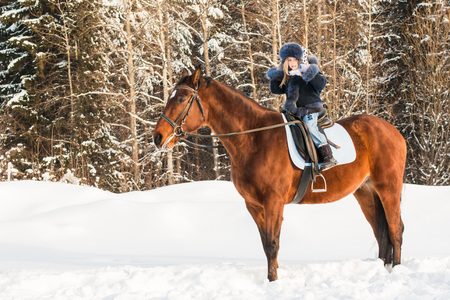 Small girl and horse in a winter dayの写真素材