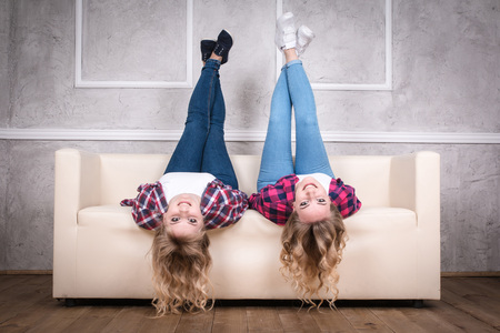 Two beautiful friendly sisters on the sofa in the roomの写真素材