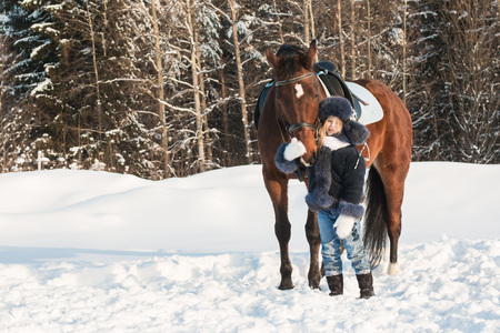 Small girl and horse in a winter dayの写真素材
