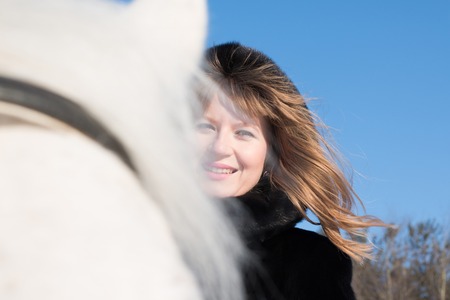 Nice girl and white horse in a forest in a winter dayの写真素材