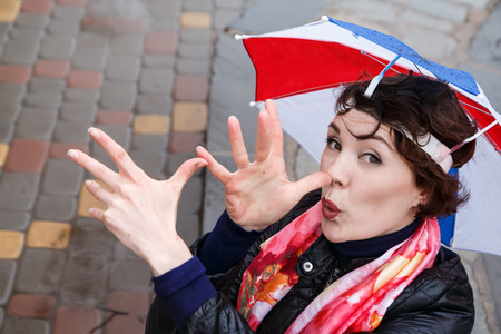 Emotional girl with colorful umbrella on her head in the park in a rainy dayの写真素材