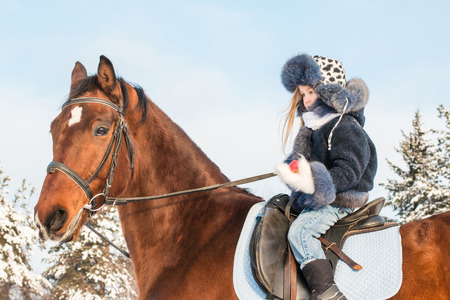 Small girl and horse in a winter dayの写真素材