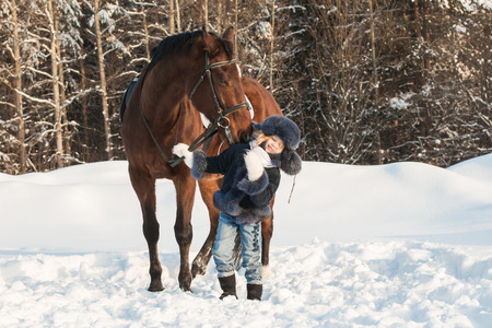 Small girl and horse in a winter dayの写真素材