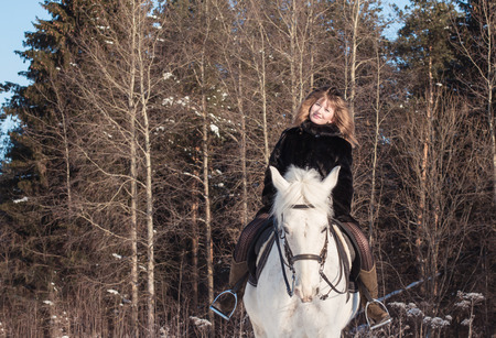 Nice girl and white horse in a forest in a winter dayの写真素材