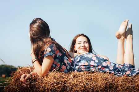 Mother and daughter in an autumn field with hay stackの写真素材