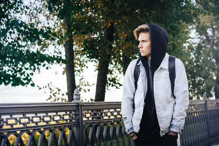 Boy teenager walks on the street in an autumn
