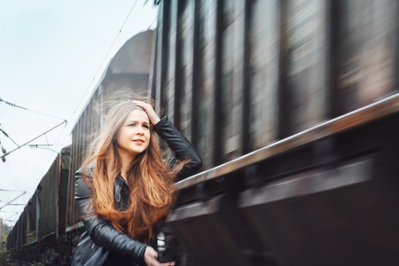 Nice girl on a railway road near moving trainの写真素材
