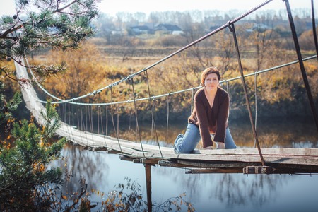 Woman on the suspension bridge in autumnの写真素材