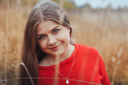 Beautiful girl in red dress in a yellow fieldの写真素材