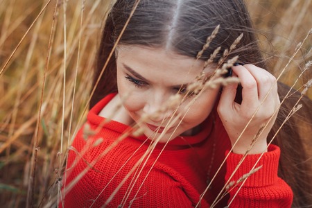 Beautiful girl in red dress in a yellow fieldの写真素材