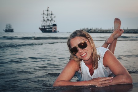 Blond woman on the beach in a water of the seaの写真素材