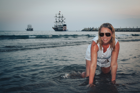 Blond woman on the beach in a water of the seaの写真素材