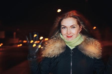Portrait of a nice girl in a warm coat in a dark cityの写真素材