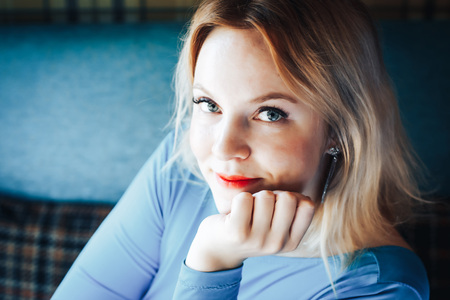 Blond woman in blue dress in cafeの写真素材