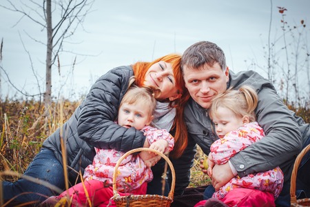 Happy family with two 1 year old girls have rest in a yellow fieldの写真素材