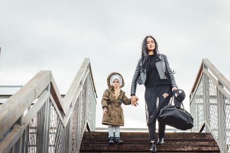 Beautiful small girl walk with mother on the stairs outdoorsの写真素材