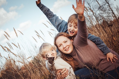 Happy woman and two sons in a field in an autumn dayの写真素材