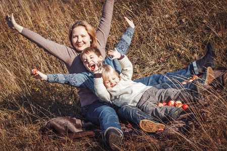 Happy woman and two sons in a field in an autumn dayの写真素材