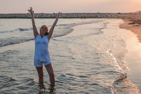 Blond woman on the beach near sea or ocean in the evening during sunsetの写真素材