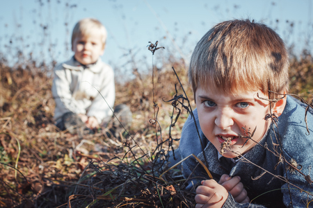 Two boys brother have fun in the field in an autumn day. The concept of friendshipの写真素材