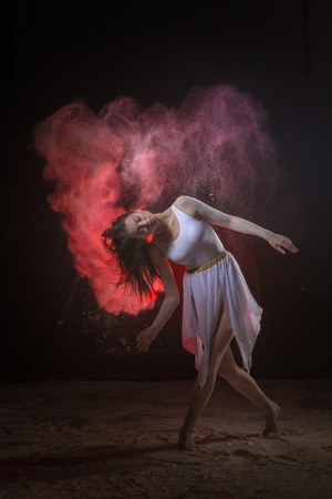 Beautiful slim female dancer in white dress in studio during Powder Photo Shoot with colored lightの写真素材